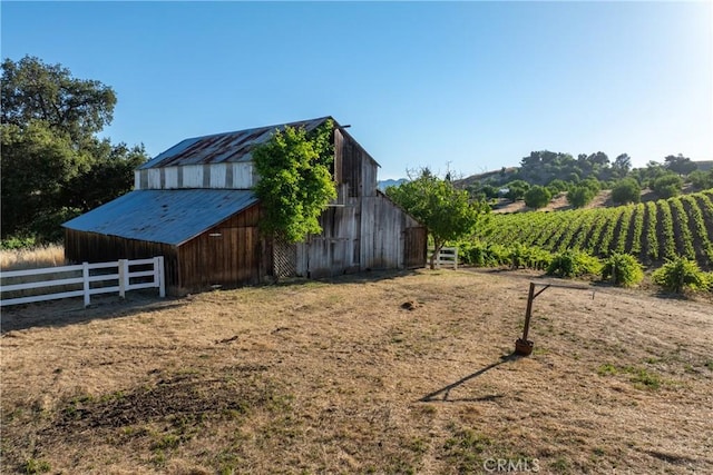 exterior space featuring a barn, a rural view, fence, and an outdoor structure