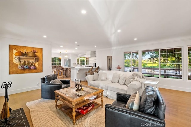 living area with recessed lighting, ornamental molding, baseboards, and light wood finished floors