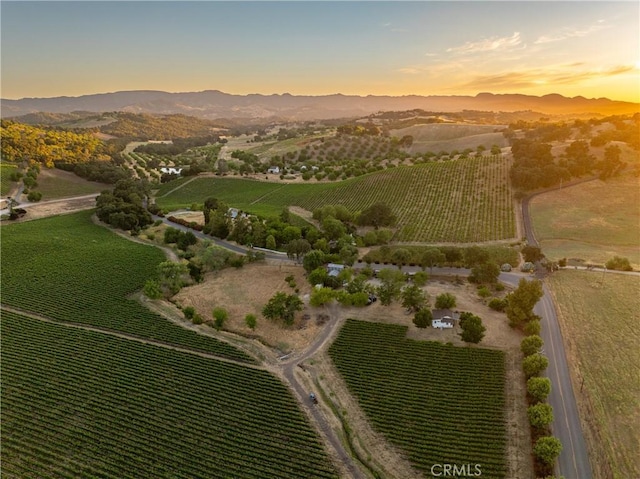 aerial view at dusk featuring a mountain view and a rural view