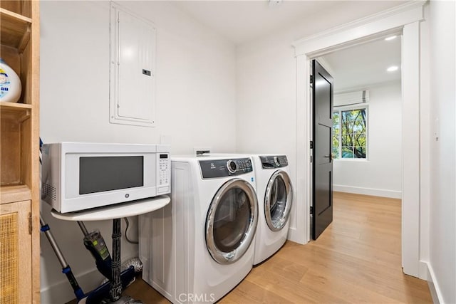 laundry room featuring electric panel, laundry area, independent washer and dryer, baseboards, and light wood-style floors