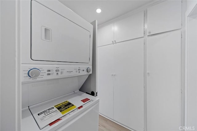 laundry room featuring light wood-type flooring and stacked washing maching and dryer