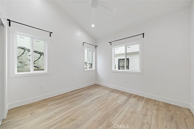 spare room featuring a wealth of natural light, light hardwood / wood-style flooring, ceiling fan, and high vaulted ceiling