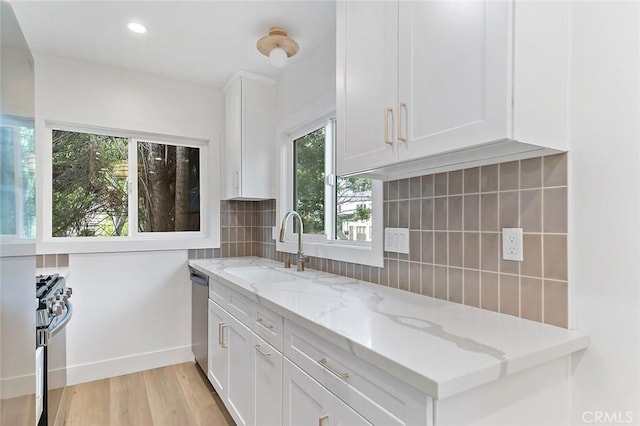 kitchen featuring light stone countertops, white cabinetry, backsplash, and appliances with stainless steel finishes