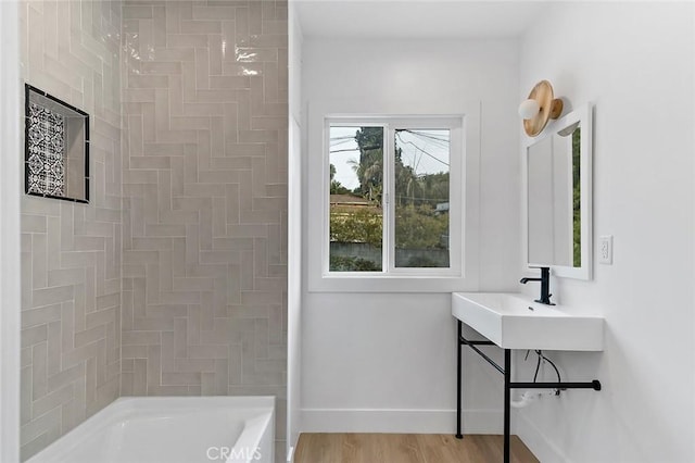 bathroom featuring hardwood / wood-style floors,  shower combination, and sink