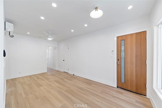 spare room featuring ceiling fan, light wood-type flooring, and an AC wall unit