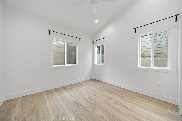 spare room featuring ceiling fan, light wood-type flooring, and lofted ceiling