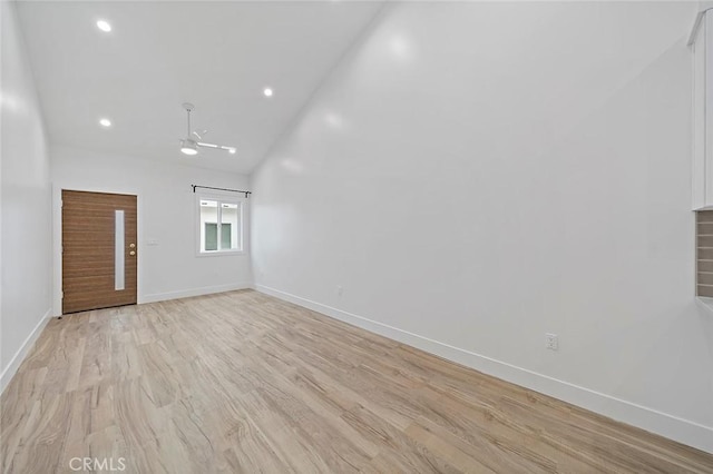 unfurnished room featuring ceiling fan, light wood-type flooring, and vaulted ceiling