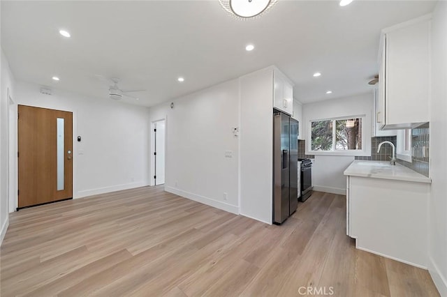 kitchen with white cabinets, appliances with stainless steel finishes, light hardwood / wood-style flooring, and sink