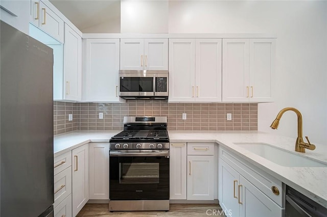 kitchen featuring decorative backsplash, sink, white cabinets, and stainless steel appliances