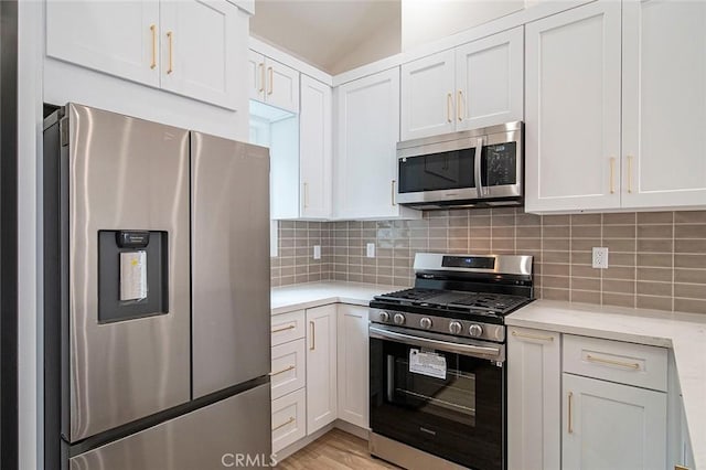 kitchen featuring decorative backsplash, light stone countertops, white cabinetry, and stainless steel appliances