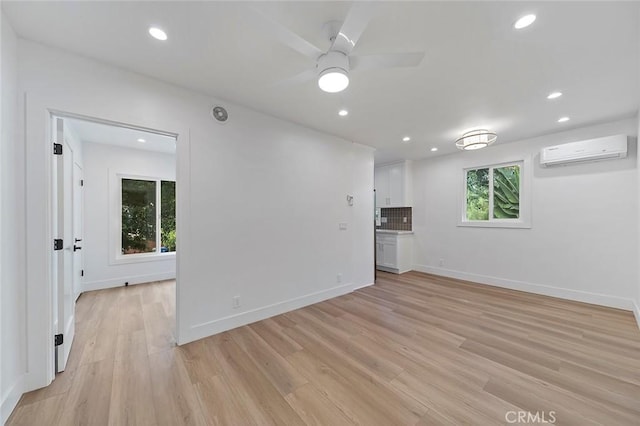 empty room with an AC wall unit, ceiling fan, and light hardwood / wood-style flooring