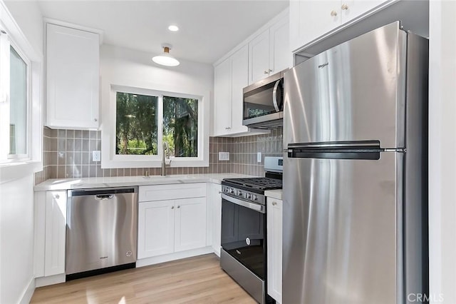 kitchen featuring white cabinets, backsplash, stainless steel appliances, and sink