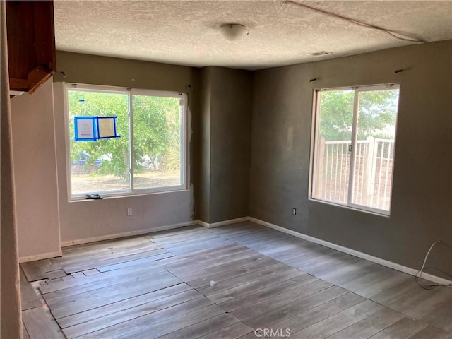 spare room with a textured ceiling and light hardwood / wood-style flooring