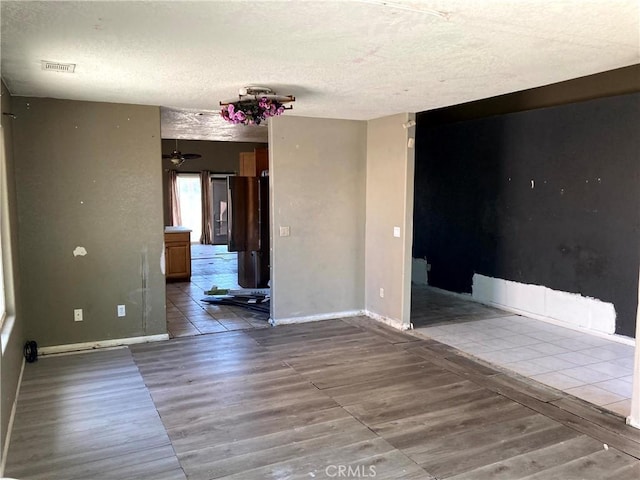 empty room featuring ceiling fan, a textured ceiling, and light wood-type flooring