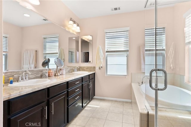 bathroom with tile patterned flooring, vanity, plenty of natural light, and tiled tub