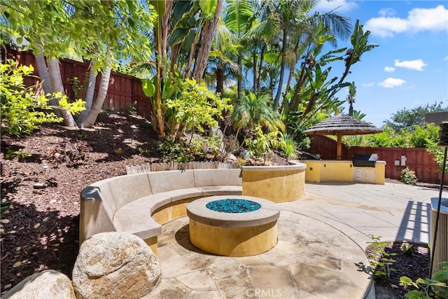 view of patio with an outdoor kitchen and a fire pit