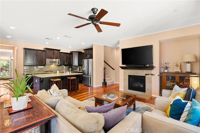 living room with ceiling fan, sink, and light hardwood / wood-style floors