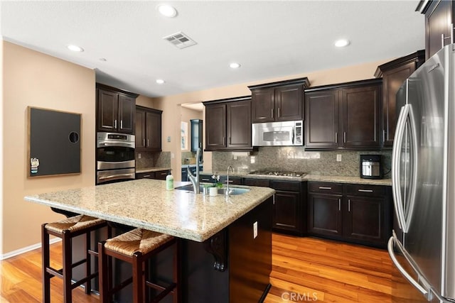 kitchen featuring backsplash, light hardwood / wood-style floors, a breakfast bar area, and appliances with stainless steel finishes