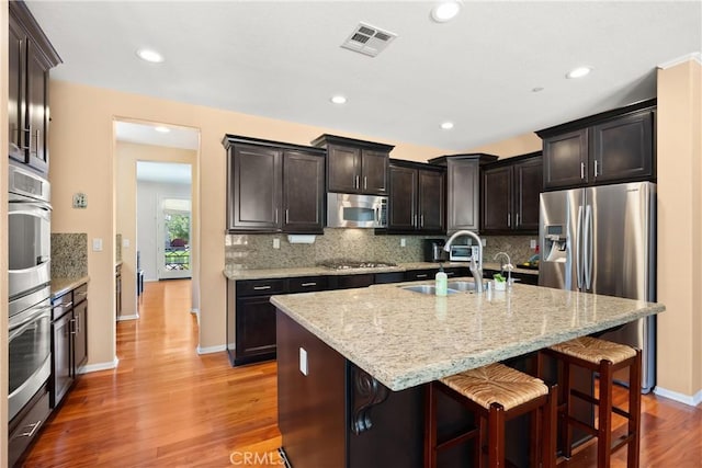 kitchen featuring a breakfast bar area, sink, a center island with sink, and appliances with stainless steel finishes