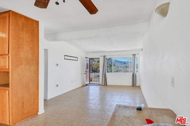 spare room featuring vaulted ceiling with beams, ceiling fan, and light tile patterned flooring