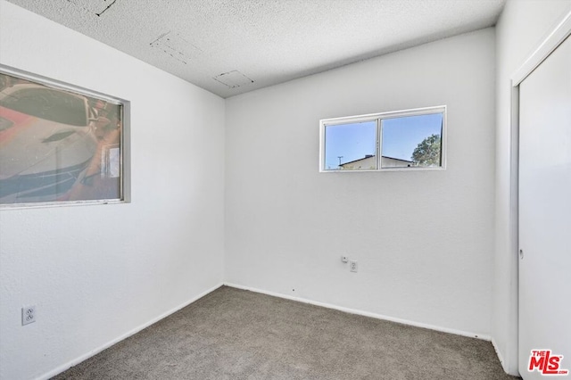 empty room featuring a textured ceiling and dark carpet