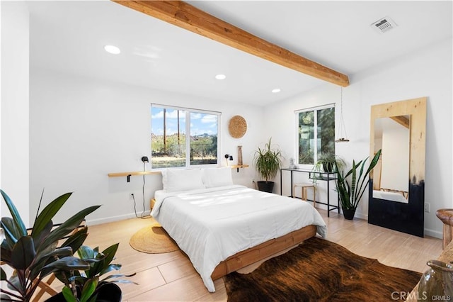 bedroom with beam ceiling and light wood-type flooring