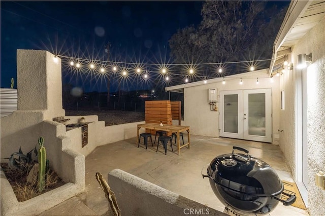 patio at night featuring a fire pit and french doors