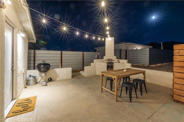 patio at twilight featuring outdoor dining space and a fenced backyard