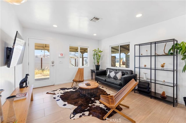 living area featuring baseboards, visible vents, and recessed lighting