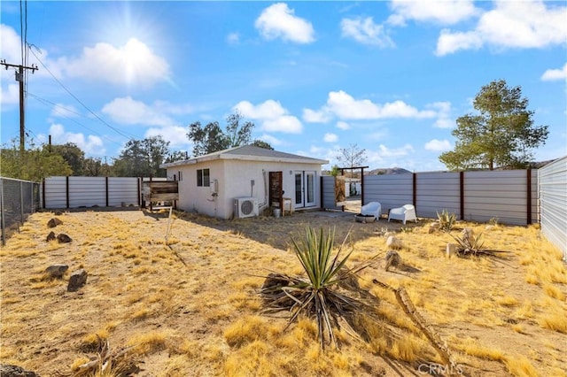 rear view of house with ac unit, a fenced backyard, and stucco siding