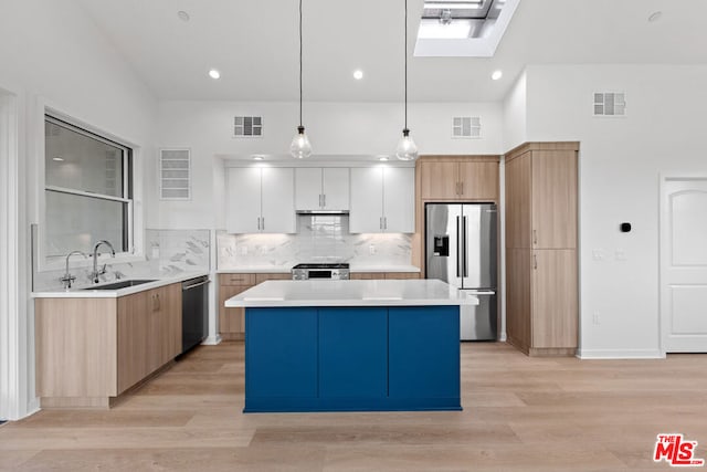 kitchen with hanging light fixtures, stainless steel appliances, a kitchen island, light hardwood / wood-style floors, and white cabinets