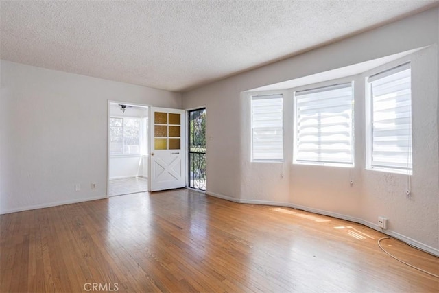 unfurnished room with hardwood / wood-style floors and a textured ceiling