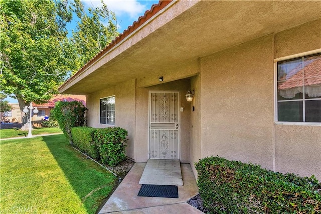 11611 Park Ln, Apple Valley, CA 92308 - property entrance with stucco siding, a tiled roof, and a lawn