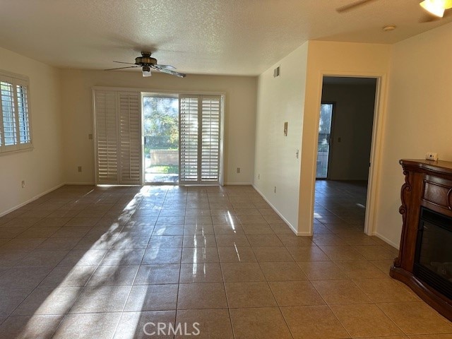 unfurnished living room featuring ceiling fan, a textured ceiling, and tile patterned floors