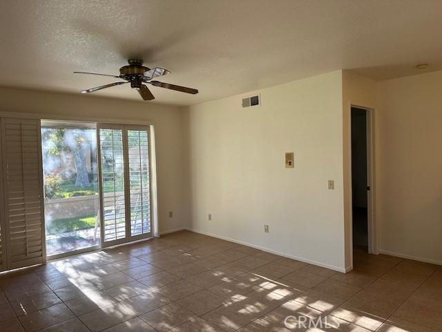 11611 Park Ln, Apple Valley, CA 92308 - tiled spare room featuring a ceiling fan, visible vents, a textured ceiling, and baseboards