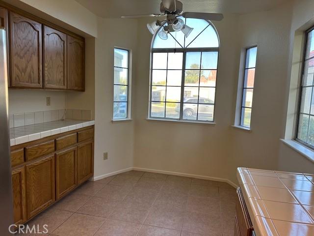 11611 Park Ln, Apple Valley, CA 92308 - unfurnished dining area featuring light tile patterned flooring, a ceiling fan, and baseboards