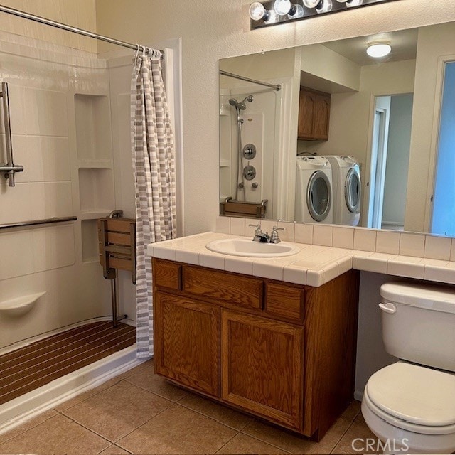 bathroom with vanity, curtained shower, washer and dryer, tile patterned floors, and toilet