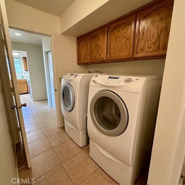 11611 Park Ln, Apple Valley, CA 92308 - clothes washing area featuring light tile patterned floors, cabinet space, and washer and clothes dryer