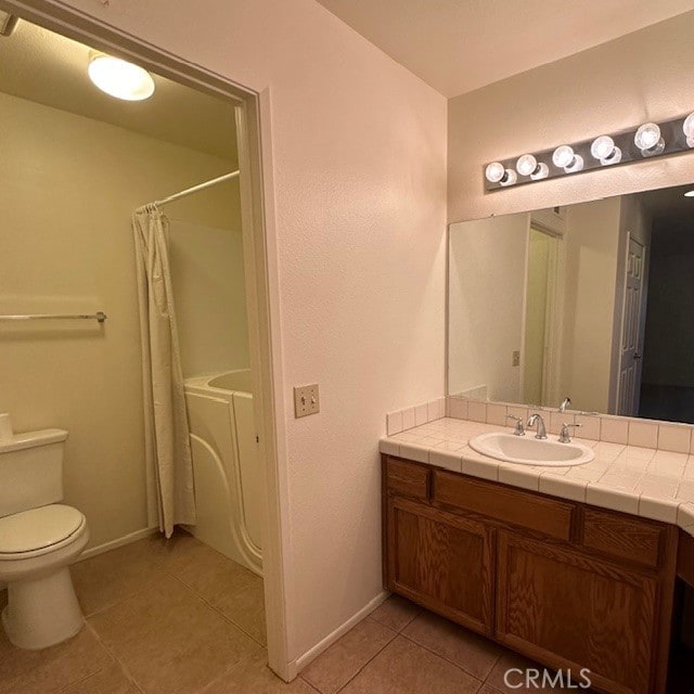 bathroom with independent washer and dryer, toilet, tile patterned flooring, and vanity