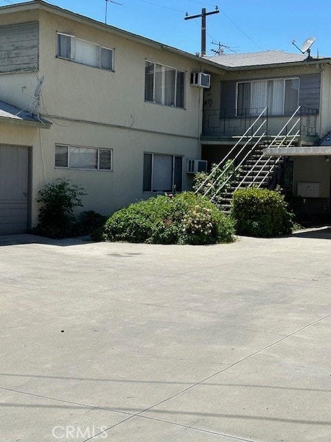 view of property featuring a garage and a wall unit AC