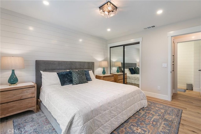 bedroom with ensuite bath, a closet, and light hardwood / wood-style flooring