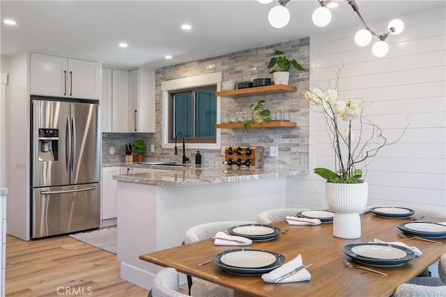 kitchen featuring white cabinets, stainless steel fridge, light wood-type flooring, and kitchen peninsula