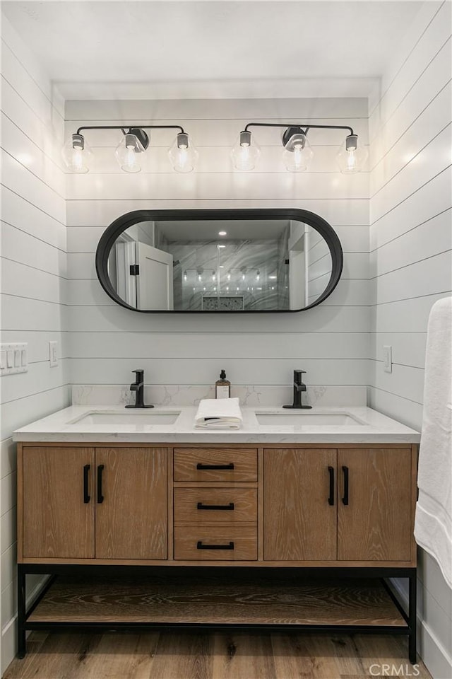 bathroom with hardwood / wood-style flooring, vanity, and wooden walls