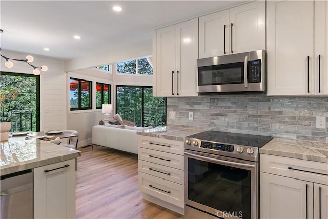 kitchen featuring stainless steel appliances, light stone counters, light hardwood / wood-style flooring, backsplash, and white cabinets