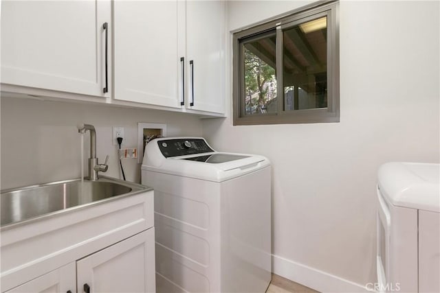 laundry area with washing machine and clothes dryer, cabinets, and sink