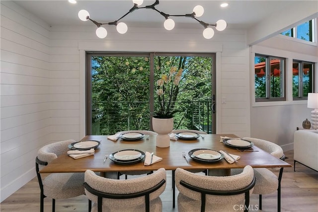 dining room featuring light wood-type flooring and wood walls