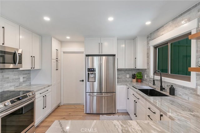 kitchen with white cabinetry, sink, light stone countertops, decorative backsplash, and appliances with stainless steel finishes