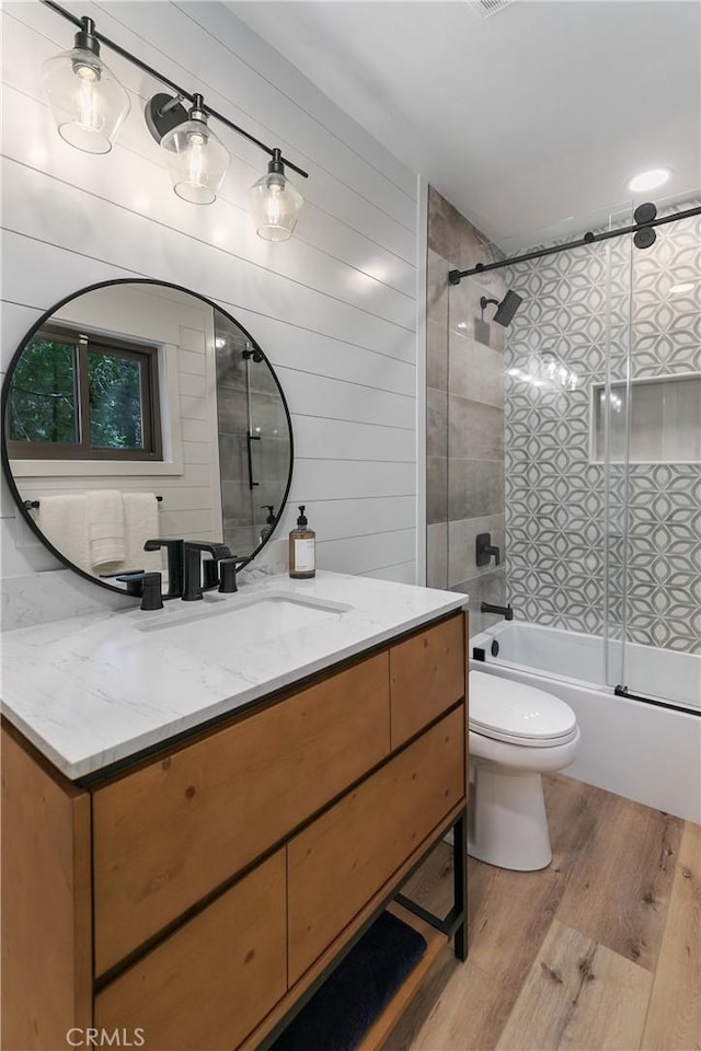 full bathroom with vanity, hardwood / wood-style flooring, toilet, and bath / shower combo with glass door