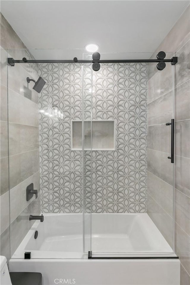 bathroom featuring combined bath / shower with glass door