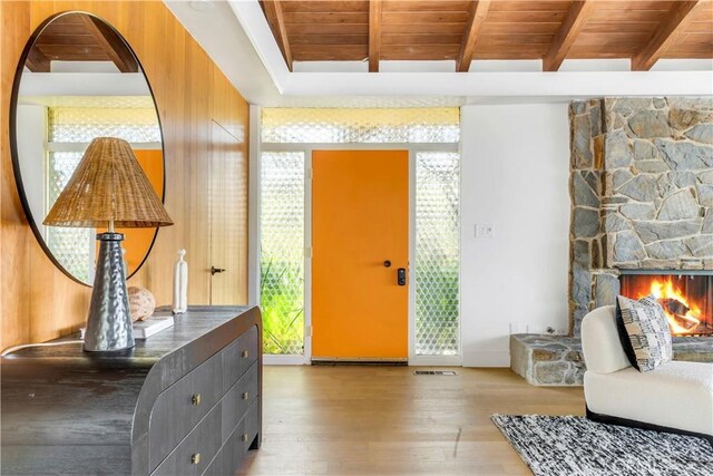 foyer entrance with beamed ceiling, light wood-type flooring, wood ceiling, and a fireplace